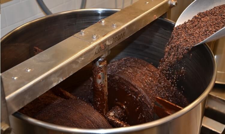 Nibs sendo colocadas na máquina melanger para produção de chocolates